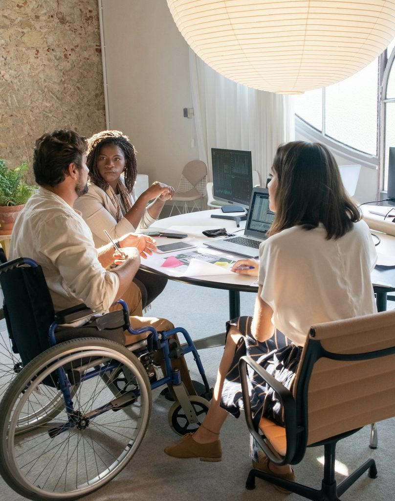 A diverse team of professionals collaborating around digital devices in a modern workspace, illustrating secure, compliant communication and protected workflows for healthcare and enterprise environments using Hypori technology.